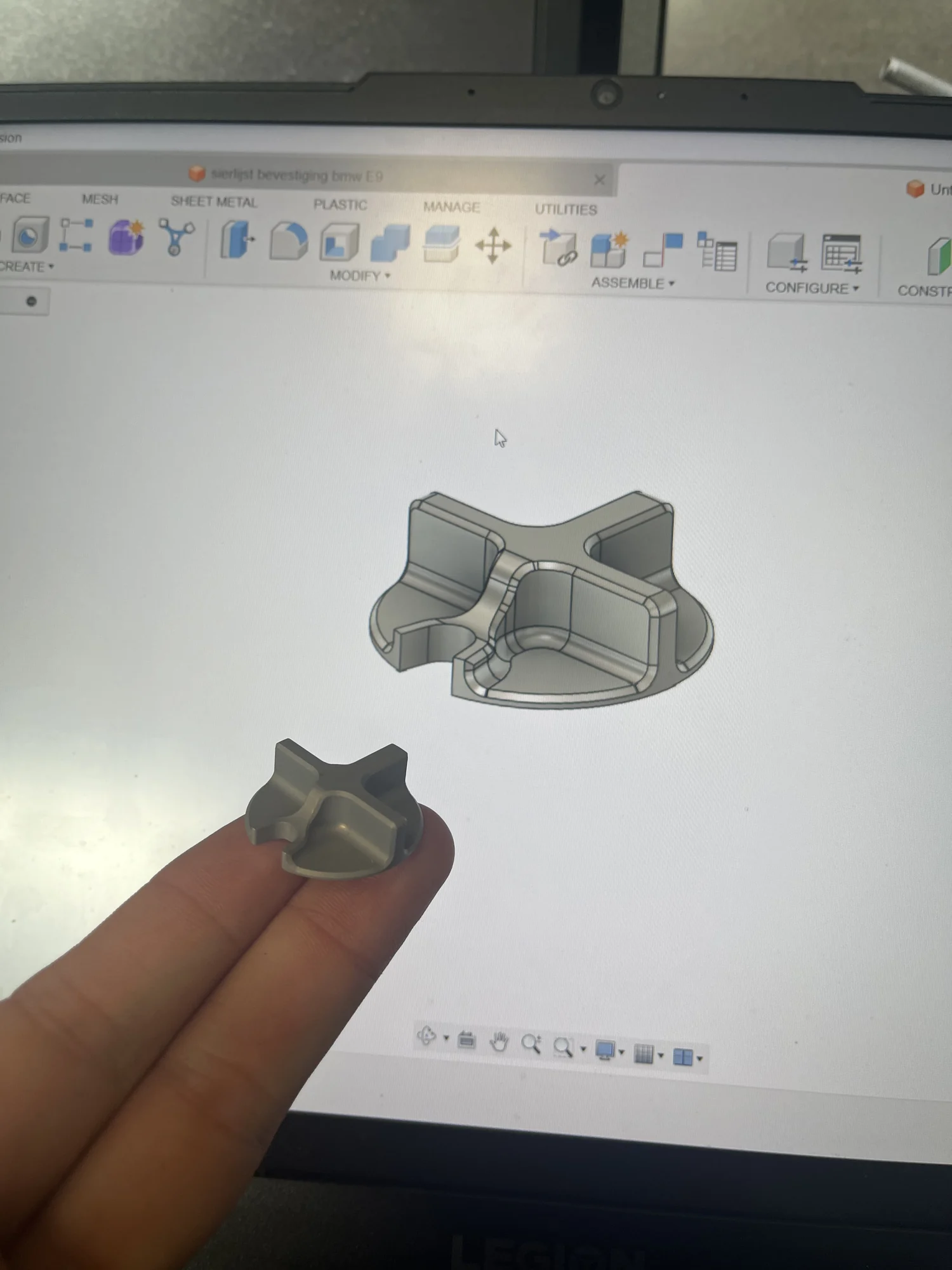 Een eerste gemaakte draaiknop, in de hand gehouden voor het CAD-model op het scherm