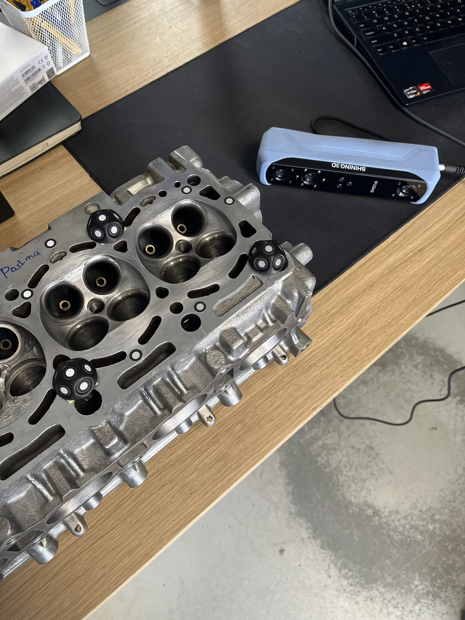 Een cilinderkop met scanmarkeringen naast een 3D-scanner